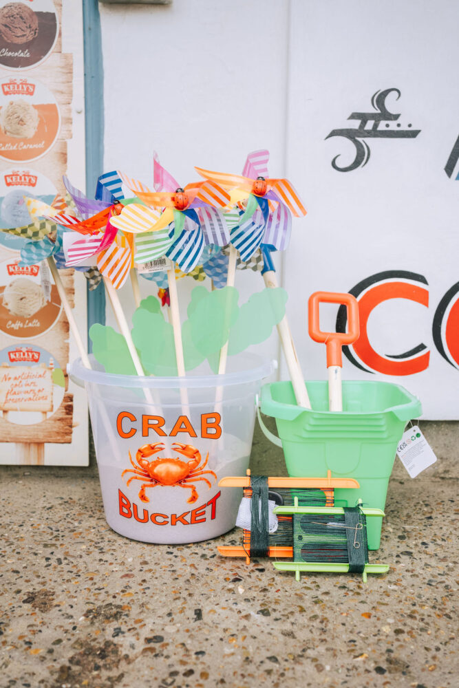 Seaside essentials in the form of buckets and spades, kite lines and a crabbing bucket next to a Kelly's Ice Cream menu