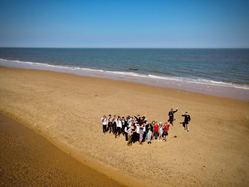 A group of young people and adults enjoy the beach at Southwold