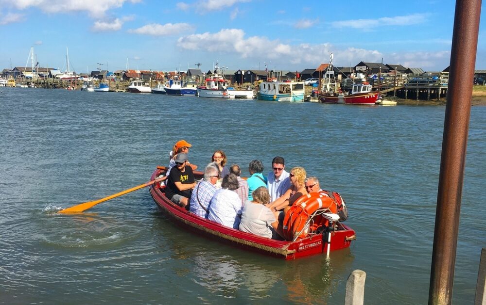 A group of people in a rowing boat on a sunny day in the harbour